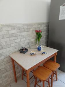 una mesa con dos tazas y un jarrón de flores en Apartament Mazury, en Olecko