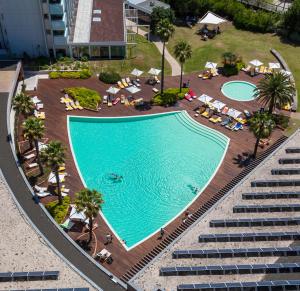 una vista sul tetto di una piscina con sedie e palme di Aqualuz Troia Mar by The Editory a Tróia