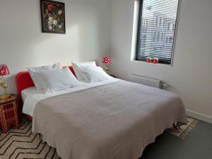 um quarto com uma cama grande com lençóis brancos e uma janela em Medina B&B hartje Arnhem em Arnhem