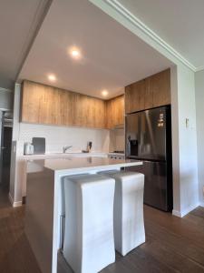 a kitchen with a stainless steel refrigerator and wooden cabinets at Near New 4br townhouse next to shopping mall in Gold Coast