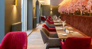 a row of tables in a restaurant with pink flowers at PLAZA Premium Columbus Bremen in Bremen