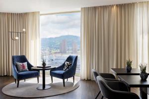 sala de estar con sillas, mesa y ventana grande en Renaissance Zurich Tower Hotel, en Zúrich