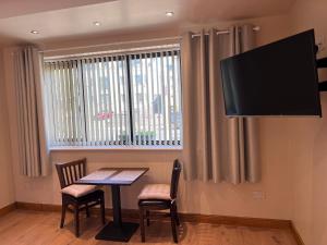 a dining room with a table and chairs and a flat screen tv at Feeney's Audubon Lodge in Galway