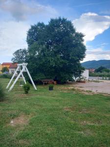 une structure blanche assise dans un champ à côté d'un arbre dans l'établissement Apartments Kruno, à Međugorje