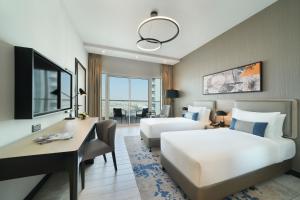 杜拜的住宿－DAMAC Hills 2 Hotel, an Edge by Rotana Hotel，酒店客房配有两张床和一张书桌