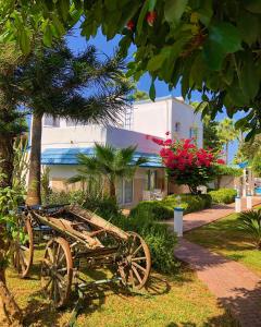 une charrette en bois assise dans l'herbe à côté d'un bâtiment dans l'établissement Hotel PINE BAY CLUB, à Kyrenia