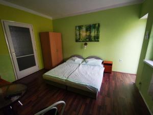 een slaapkamer met een bed in een kamer met groene muren bij Paksy Apartman in Harkány