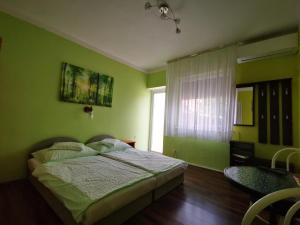 een groene slaapkamer met een bed en een raam bij Paksy Apartman in Harkány