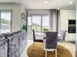 a dining room with a table and chairs and windows at Rancho Tá-Mar Apartment Nazaré Beach in Nazaré