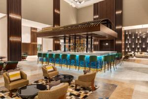 een lobby met een bar met groene en blauwe stoelen bij Wyndham Bukhara in Bukhara