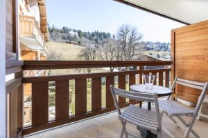 uma mesa e cadeiras numa varanda com vista em Résidence Hôtel Rent - Megève Centre em Megève