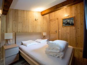 um quarto com uma cama com lençóis brancos e almofadas em Résidence Hôtel Rent - Megève Centre em Megève