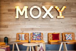 um restaurante com cadeiras laranja e um sinal de mox na parede em Moxy Rust em Rust