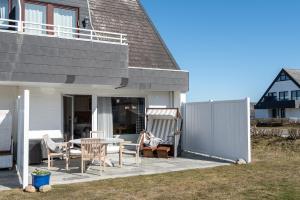 une terrasse avec une table et des chaises à côté d'une maison dans l'établissement Nordseegruß 1, à Wenningstedt