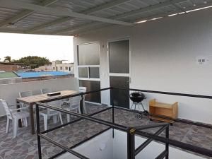 einen Balkon mit einem Tisch, Stühlen und einem Grill in der Unterkunft Paradisíaco Apt 360º Palmira in Palmira