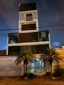 un edificio alto con palmeras delante en Talli Hotel, en Curitiba