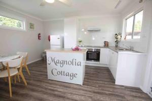 - une cuisine avec des appareils blancs, une table et des chaises dans l'établissement Magnolia Cottage, à Coffs Harbour