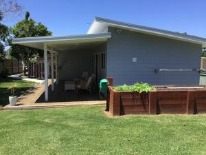 une maison avec une terrasse couverte dotée d'une boucherie pour le feu dans l'établissement Magnolia Cottage, à Coffs Harbour