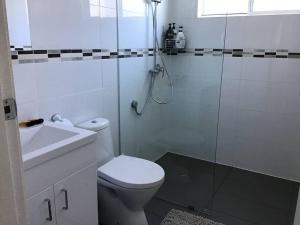 La salle de bains est pourvue d'une douche, de toilettes et d'un lavabo. dans l'établissement Magnolia Cottage, à Coffs Harbour