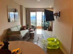 ein Wohnzimmer mit einem Sofa, einem Tisch und einem TV in der Unterkunft Depto a estrenar increíble vista 180º Cocha in Cochabamba