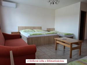 um quarto com uma cama, uma mesa e um sofá em Európa Penzión em Štúrovo