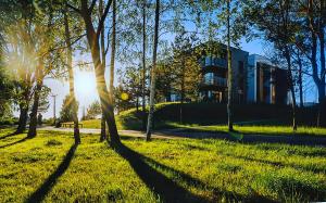 un grupo de árboles en un parque con un edificio en Gilužio Rivjera, en Vilna