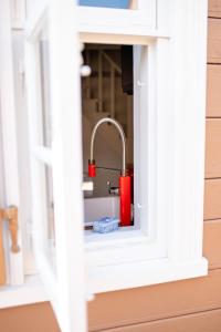 una casa de juguete con una ventana con cerradura roja en i’dille Brīvdienu māja, en Kuldīga