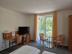 ein Hotelzimmer mit einem Bett, einem Tisch und einem Fenster in der Unterkunft Hotel Siebeneichen  in Meißen