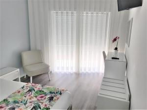 um quarto com uma cama, uma cadeira e uma janela em Hotel Ancora Mar na Nazaré