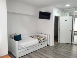 um quarto com uma cama branca e uma televisão na parede em Hotel Ancora Mar na Nazaré