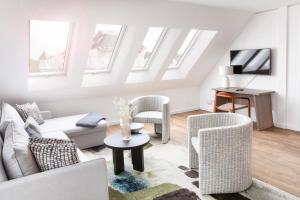 d'un salon avec des meubles blancs et des fenêtres. dans l'établissement Seehuus Duhnen Apartments, à Cuxhaven