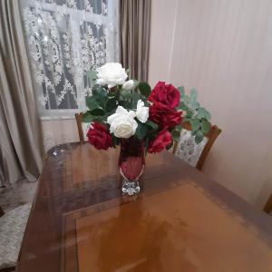 un vase rempli de fleurs rouges et blanches sur une table dans l'établissement Ideal, à Akhaltsikhé