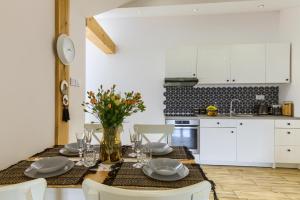 cocina con mesa de comedor y armarios blancos en Apartament Abra 1 Rynek 8, en Muszyna