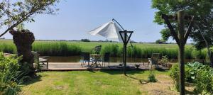 een terras met een tafel en stoelen en een parasol bij Garden house Zuiderwoude in Zuiderwoude