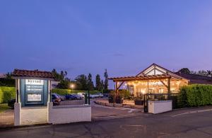 un bâtiment avec un panneau en face d'un parking dans l'établissement Kyriad Lyon Est - Bron Eurexpo Le Cottage, à Bron