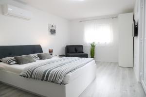 een witte slaapkamer met een groot bed en een stoel bij Imperium Rooms Zagreb Airport in Velika Gorica