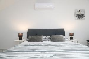 een witte slaapkamer met een groot bed met 2 lampen bij Imperium Rooms Zagreb Airport in Velika Gorica