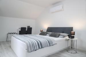 een wit bed met zwart-witte lakens en kussens bij Imperium Rooms Zagreb Airport in Velika Gorica