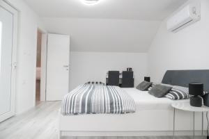 een witte slaapkamer met een bed met zwart-witte kussens bij Imperium Rooms Zagreb Airport in Velika Gorica