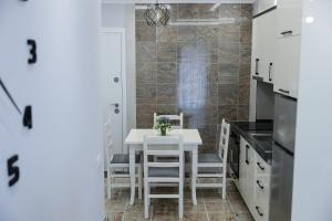 - une cuisine avec une table et des chaises blanches dans l'établissement Fishta apartments Q5 35, à Velipojë