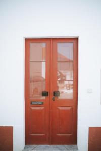 eine rote Tür mit zwei Fenstern auf einem weißen Gebäude in der Unterkunft Casa do Castelo in Lourinhã