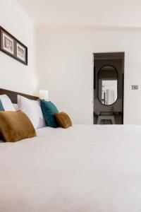 una camera da letto con un grande letto bianco con cuscini di Capricorn Hotel Suva a Suva