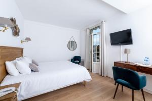 een witte slaapkamer met een bed en een televisie bij Hôtel Beau Site - Cap d'Antibes in Antibes