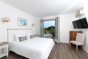 een witte slaapkamer met een bed en een televisie bij Hôtel Beau Site - Cap d'Antibes in Antibes