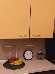 a kitchen counter with a clock and fruit on it at Mini studio aproape de centru in Bucharest