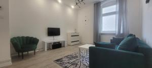 uma sala de estar com duas cadeiras e uma televisão em Apartament CityStation em Wałbrzych