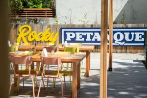 un restaurant avec des tables et des chaises en bois devant une clôture dans l'établissement RockyPop Grenoble Hotel, à Grenoble