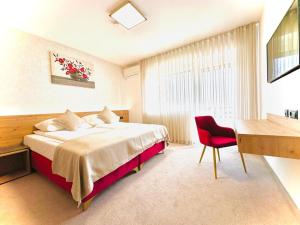 1 dormitorio con cama, escritorio y silla roja en Medirooms Apartments, en Feldkirchen bei Graz