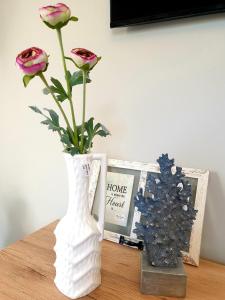 un vase blanc avec des fleurs sur une table à côté d'une photo dans l'établissement EcoStay-Scandy,2bdr cozy apartment by the sea in Alimos, à Athènes