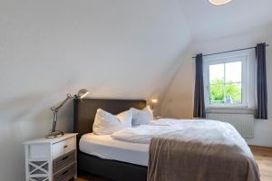 een slaapkamer met een bed met een lamp en een raam bij Boutique 54° Nord in Büsum